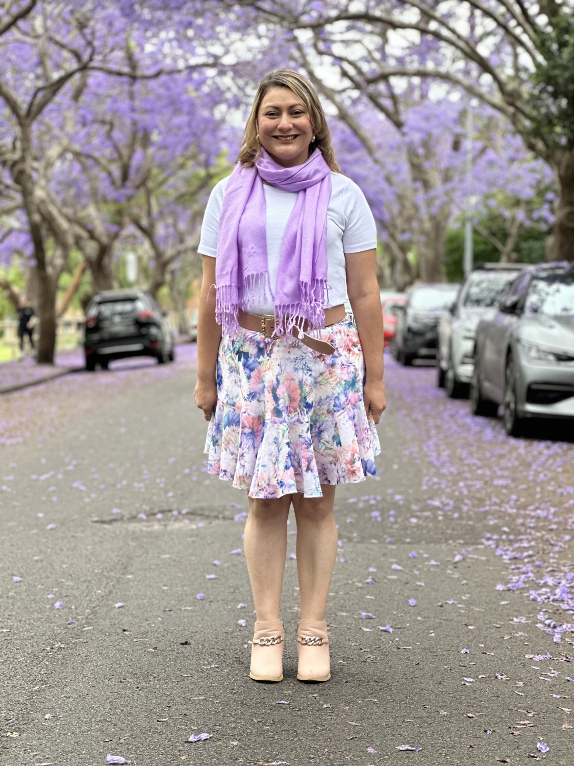 Jessica in a floral skirt on a jacaranda-lined street