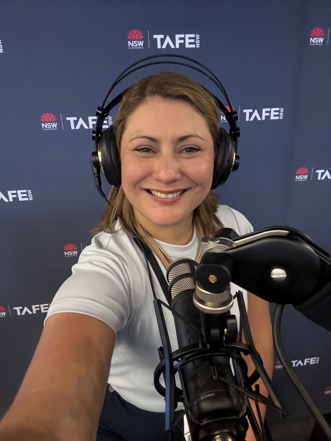Jessica smiling at a podcast microphone with headphones